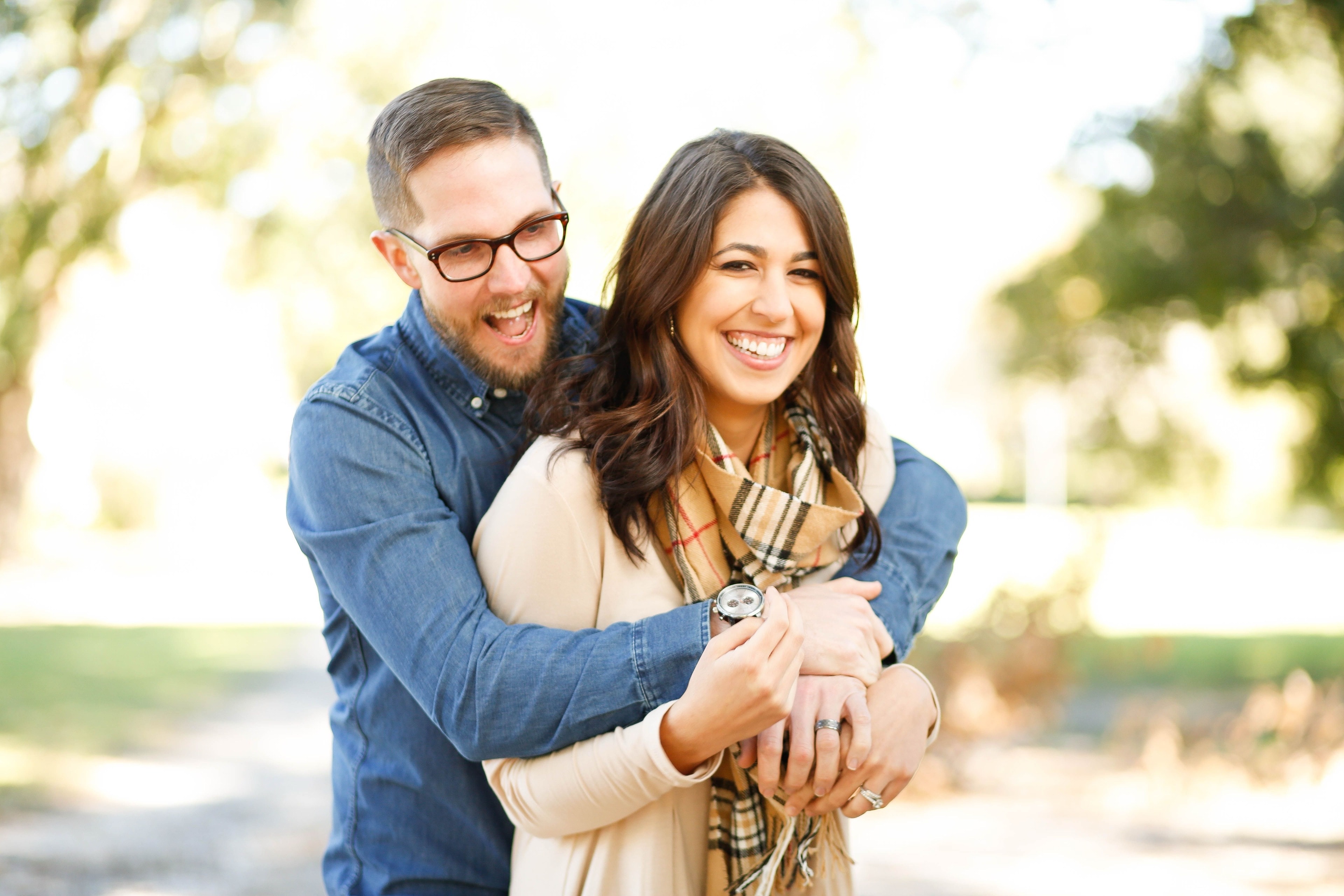 Two people laughing together outdoors on an autumn afternoon.